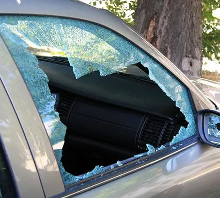 A car with broken windows and shattered glass.