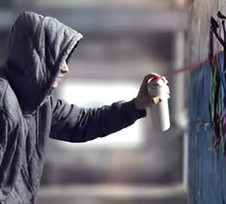 A person spray painting on the side of a building.