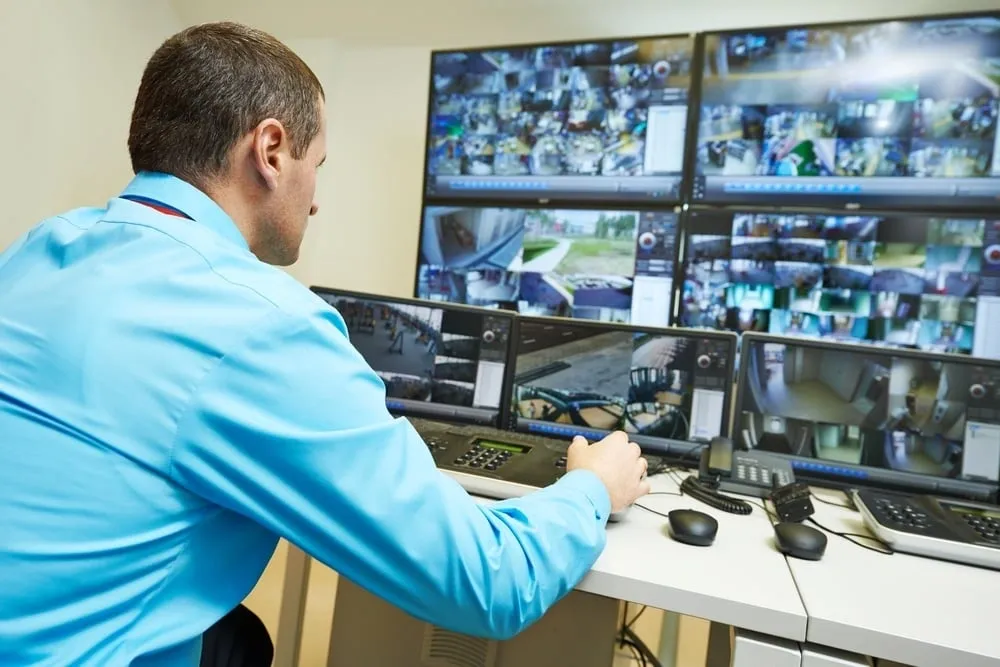 A man is looking at multiple monitors in the room.