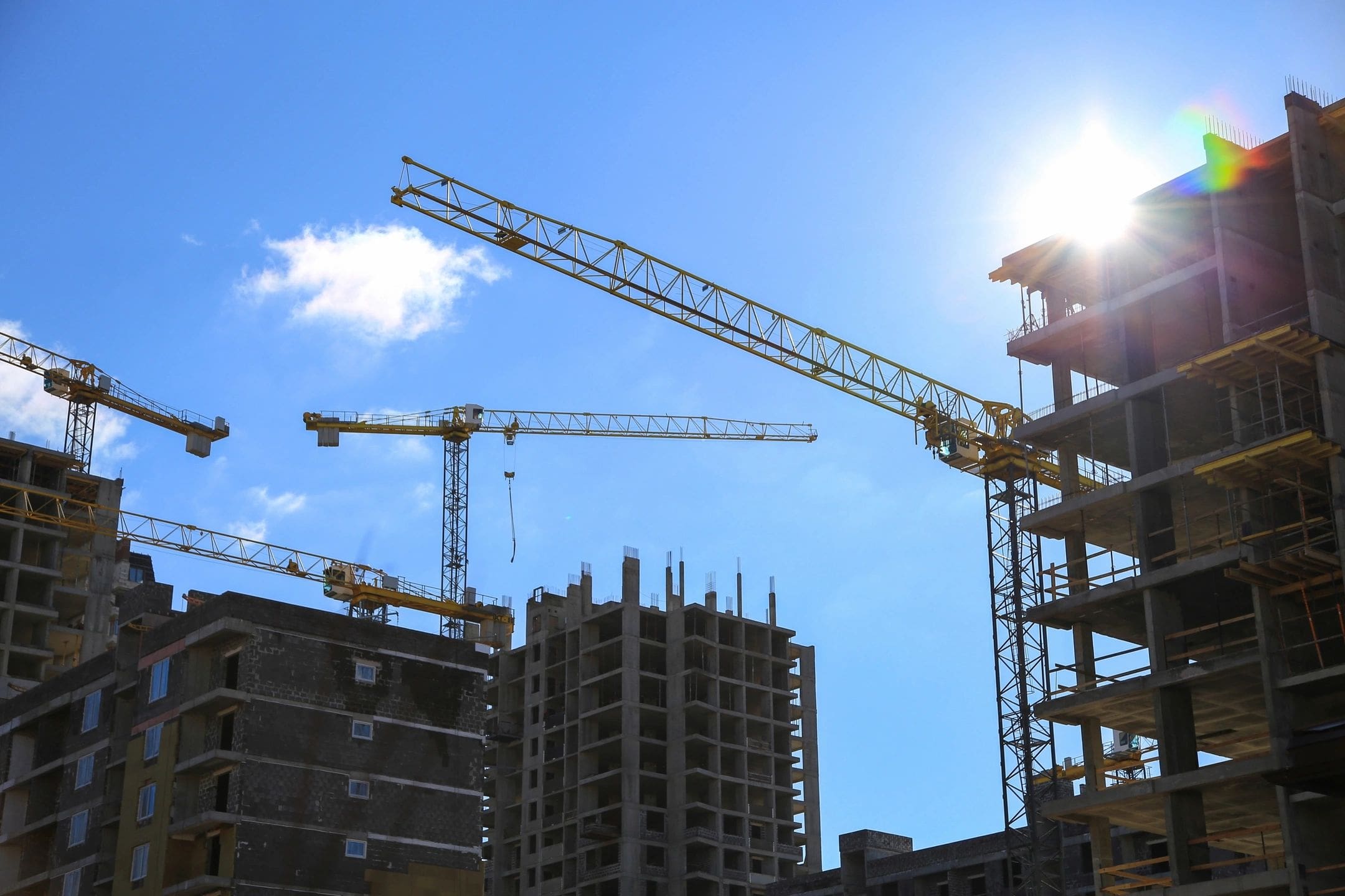 A group of cranes in front of some buildings.